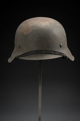 un vieux casque posé sur un support, sur fond noir