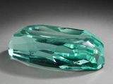 une pierre de couleur émeraude posée sur une surface grise