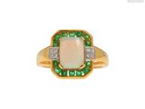 un gros plan d'une bague sertie d'un oplite et d'une émeraude