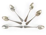 six cuillères en argent disposées en cercle sur une surface blanche