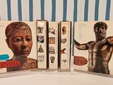 two books on a table with a statue of a man in the middle