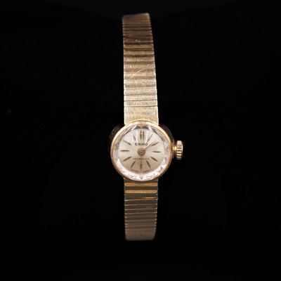 a close up of a gold watch on a black surface