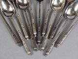 six spoons and a spoon rest in a circle on a table