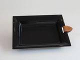 une petite assiette noire avec un manche en bois posée sur une table blanche