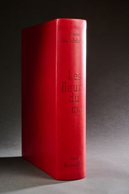 un livre rouge posé sur une table, devant un fond noir