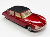 une petite voiture rouge avec un toit noir posée sur une surface blanche