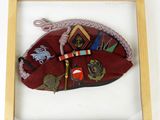 a framed picture of a red hat with a lot of different things on it