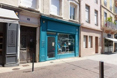 a blue store front on a street corner with buildings in the background