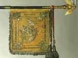 a gold and black banner hanging from a pole