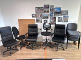 Plusieurs chaises de bureau noires sont alignées dans une pièce où des tableaux sont accrochés au mur.