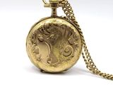 a gold pocket watch with a chain on a white background