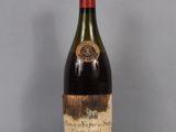 an old bottle of wine sitting on top of a glass table
