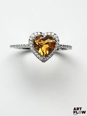 un gros plan d'une bague en forme de cœur sertie de diamants, sur fond blanc