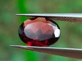 un gros plan d'une pierre rouge tenue par une pince