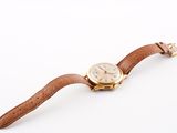 a close up of a wrist watch with a brown leather strap