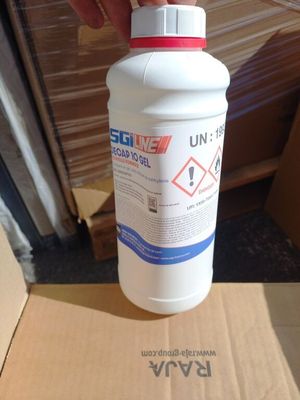 une main tenant une bouteille remplie de liquide devant une boîte en carton