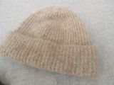 a white sweater with a beige knitted hat on it