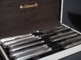 a box that has six silver and black pens in it