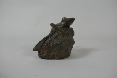 figurine of a frog sitting on a rock on a white background