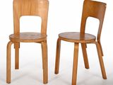 deux chaises en bois assises l'une à côté de l'autre sur une surface blanche