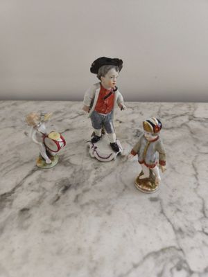trois figurines représentant un garçon et une fille posées sur une table en marbre