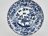 blue and white plate with flowers and birds on it on a stand