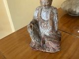 une statue représentant une personne assise sur une table en bois