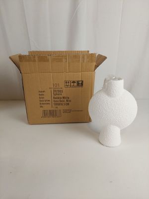 un vase blanc posé à côté d'un carton sur une table