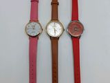 three different colored watches sitting next to each other on a white surface