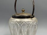 an antique glass teapot with a metal handle on a grey background