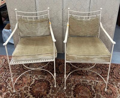une paire de chaises en fer blanc avec des coussins verts, posées sur un tapis
