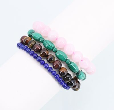 un gros plan sur une pile de trois bracelets composés de perles de différentes couleurs