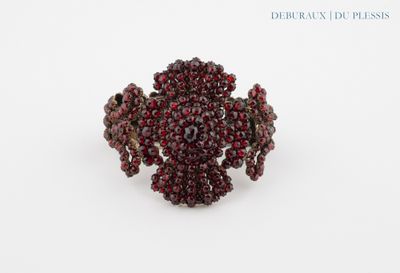 un gros plan d'une bague ornée de perles rouges sur une surface blanche