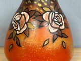 un vase orange orné de fleurs peintes, posé sur une table