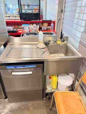a kitchen with a sink, dishwasher, and a chair in it