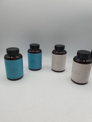 un ensemble de quatre bouteilles remplies de liquide posées sur une surface blanche