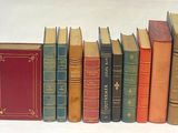 several old books are lined up in a row on a white surface