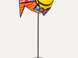 brightly colored fish figurine on a black stand on a white background
