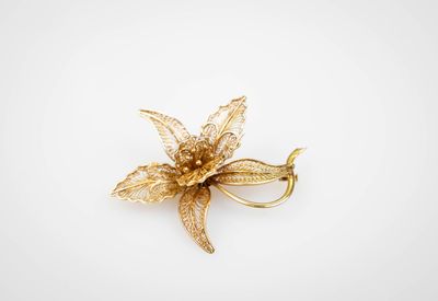 un gros plan d'une broche en forme de fleur dorée sur fond blanc