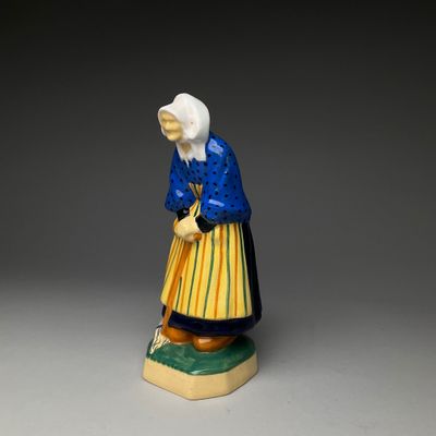 an old figurine of a woman with a blue dress and yellow skirt