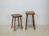 two wooden stools sitting next to each other against a white wall