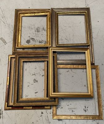 four gold picture frames sitting on top of a white table