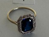 an image of a ring with a blue stone surrounded by diamonds