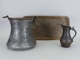 un pichet en argent et un plateau en argent posés sur une table