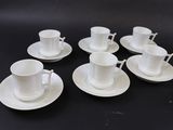 six cups and saucers sitting on a black table