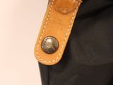 the back of a black bag with a brown leather handle