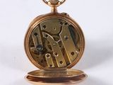 a close up of a gold pocket watch on a white surface