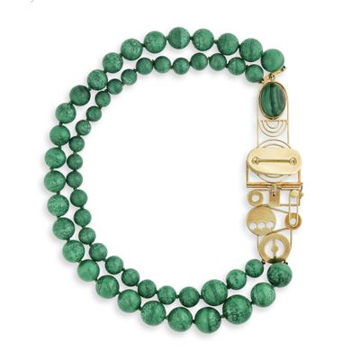 un gros plan sur un bracelet en perles vertes muni d'un fermoir doré