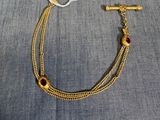 un gros plan d'un bracelet en or orné d'une pierre rouge
