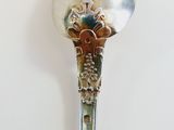 a silver spoon with a flower on it sitting on a table